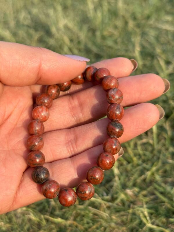 red jasper natural gem stone bracelet in left hand