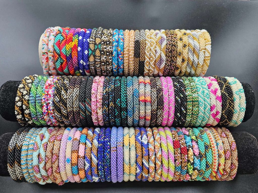 Three-tier display of colorful handmade beaded bracelets crafted with glass seed beads, showcasing various patterns and styles