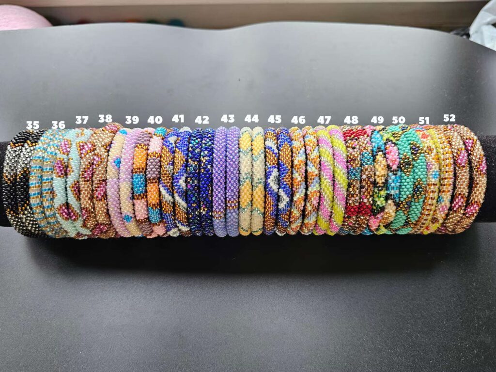Pastel-toned handmade bracelets with pink, cream, and gold glass beads, arranged on a display roll